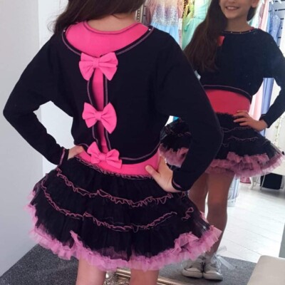 Young girl wearing Ooh la la Couture fabulous jersey crop top with gorgeous hot pink stitching and hot pink bows on the back over a jersey bodice and black & hot pink tutu skirt from a Girls Party Dress Specialist Boutique