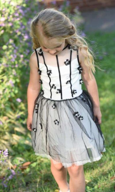 Small young girl wearing a white, grey and black Ooh La La Couture Adele Dress, from Children’s fashion specialist Silhouette London.